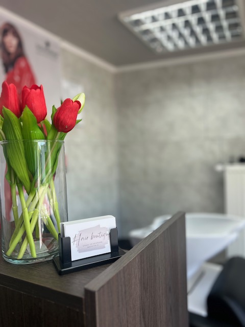Visitekaartjes van Hair Boutique naast een vaas met rode tulpen.